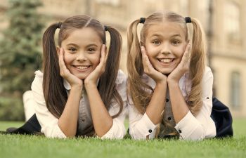 Two smiling teen schoolgirls lying on grass.