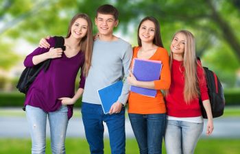 Three teenage girls and a bouy with school bags and folders.